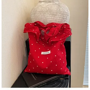 Close-up of red floral cotton tote bag with fashion label and textured fabric details