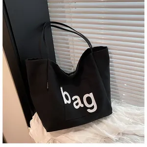 Détail du sac cabas en toile noire avec imprimé bag et étiquette tissée fashion