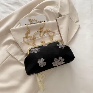 Detail of black velvet shell bag with floral embroidery and white tassel detail