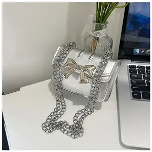 Detailed view of silver crossbody bag with metallic bow buckle and chain strap