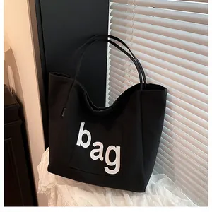 Gros plan du grand sac cabas noir en toile avec imprimé blanc BAG et étiquette