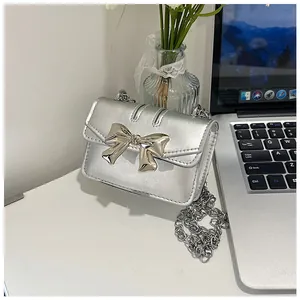 Detail of silver mini crossbody bag featuring a metallic bow and fine chain strap