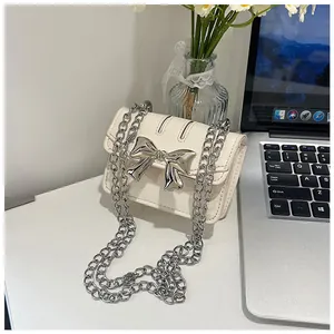 Close-up of a mini leather crossbody bag with metallic silver bow and silver chain strap