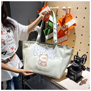 Detail of light green canvas tote bag with a cute panda graphic and sturdy shoulder strap