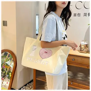 Detailed view of off-white corduroy tote bag featuring pink heart plushy embroidery