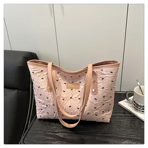 Detailed shot of pink textured tote bag featuring black bow prints and metal brand plaque