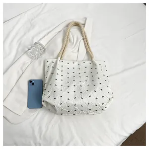 Détail d'un sac cabas plissé blanc avec motifs nœuds noirs et anses en corde tressée