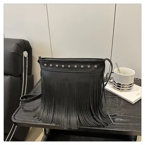 Detalle de bolso bandolera de cuero negro con tachuelas plateadas y flecos largos