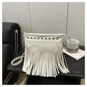 Detalle de bolso boho blanco con flecos, remaches metálicos y textura de cuero de grano fino