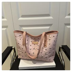 Close-up of pink pleated tote bag with black bow print and yellow brand label