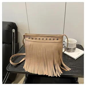Primer plano del bolso beige en cuero granulado con remaches metálicos y flecos largos