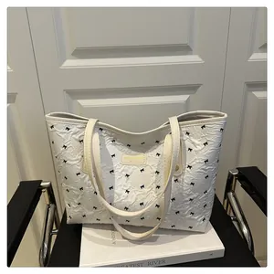 Detail of white wrinkled tote bag featuring small black bows and leather logo patch