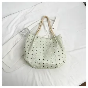 Détail du tissu gaufré menthe avec imprimés nœuds et anses en corde tressée sur le sac