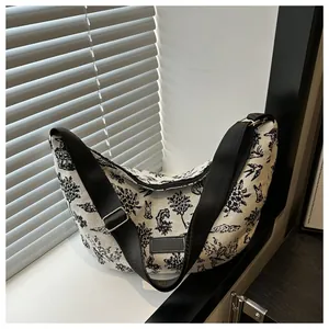 Detail of canvas crescent bag with black illustrated tree and animal prints and wide strap