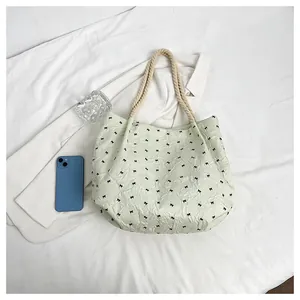 Détail du sac cabas vert clair à texture bulles, imprimé nœuds et bandoulière corde