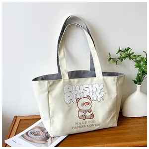 Detail view of cream canvas tote bag with panda print and sturdy double handles