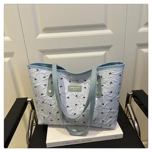 Close-up of quilted tote bag featuring light blue patterns and black bow details