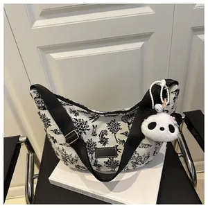 Detail of canvas tote with nature silhouette prints and a plush panda charm attachment