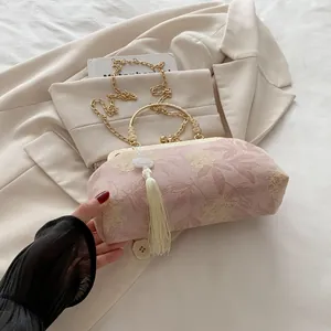 Detail of pink floral cheongsam bag with golden frame and silk tassel accessory