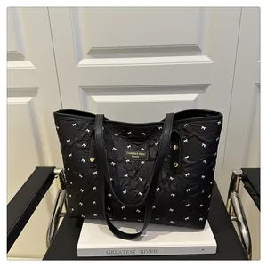 Detail of black quilted tote bag featuring white bow prints and metallic logo
