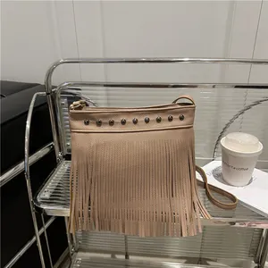 Bolso de hombro bohemio beige con flecos y tachuelas en un estante elegante
