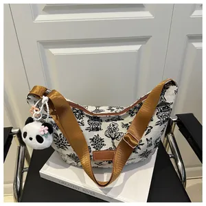 Detail of half-moon canvas bag with black landscape print and panda pendant