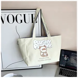 Close-up of cream corduroy tote bag featuring a cute panda print and durable handles