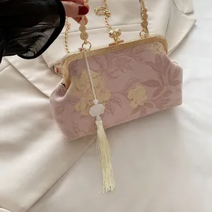 Detail of pink floral brocade handbag with golden clasp and long white silk tassel