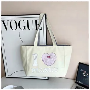 Detail of off-white corduroy tote bag featuring I Heart Plushy graphic design on wall