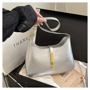 Detail of silver crescent moon bag with metallic finish and gold vertical turn-lock closure
