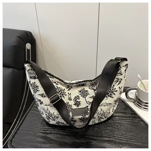 Close-up of crescent canvas crossbody bag with Toile de Jouy print and wide strap