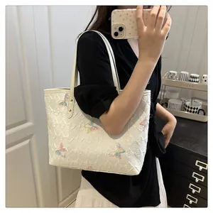 Détail d'un sac cabas blanc avec matelassage en losanges 3D et broderie papillon colorée
