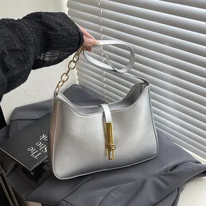 Chic silver underarm bag with gold metallic lock and chain strap on minimalist background