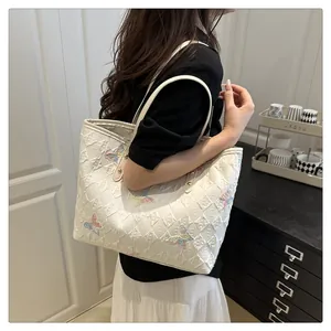 Détail d'un sac cabas blanc avec motif matelassé et broderies de papillons colorés