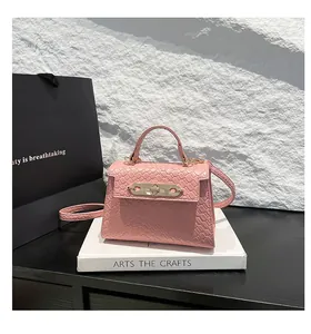 Detail of pink faux leather handbag with woven texture and gold twist-lock closure