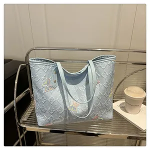 Détail du sac cabas bleu clair avec texture gaufrée 3D et broderie papillon arc-en-ciel