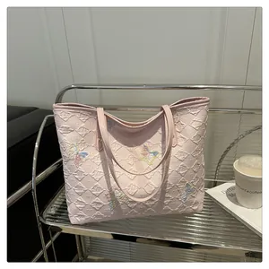 Détail du sac fourre-tout rose matelassé avec broderies papillons colorées et fines anses