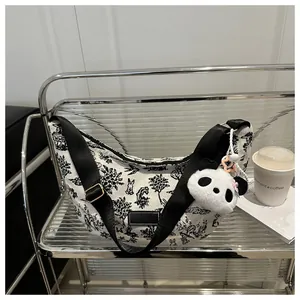 Detail of printed crescent tote bag with panda plush charm and adjustable strap