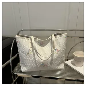 Détail du sac cabas blanc avec broderies de papillons colorés et texture gaufrée élégante