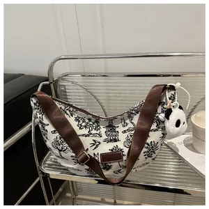 Detail view of canvas hobo bag featuring landscape print and panda plush charm accessory