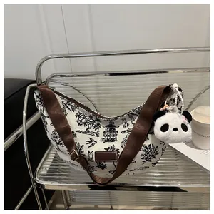Detail of canvas crescent bag with landscape print, brown strap and panda charm