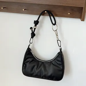 Dettaglio borsa hobo in pelle nera con tracolla annodata e sfere metalliche argentate