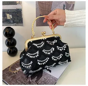 Detail of a black sequin evening bag with gold metal frame and round ring handle