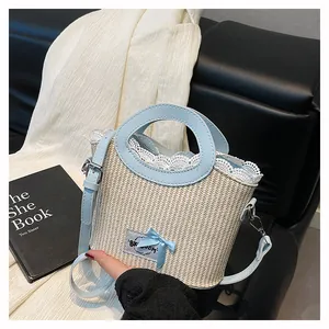 Détail du sac en paille crème avec bandoulière en cuir bleu clair et bordure en dentelle