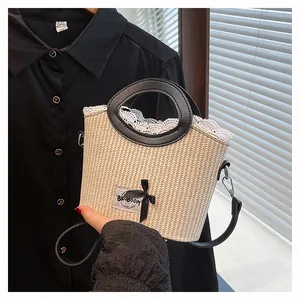 Détail d'un sac en paille tressée avec bordure en dentelle blanche et anses noires