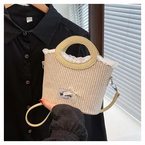 Détail du sac seau en paille avec bordure en dentelle blanche, nœud en soie et poignée