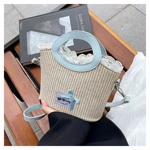 Détail du sac en paille avec poignées en cuir bleu et bordure en dentelle blanche