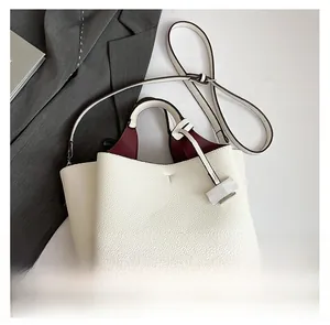 Top view of white pebble leather tote bag with burgundy lining and metal bottom studs