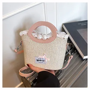 Détails des poignées en cuir rose et bordure en dentelle blanche sur le sac en paille