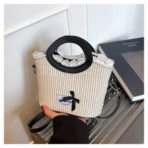 Détail du sac en paille tressée beige avec bordure en dentelle blanche et anses noires
